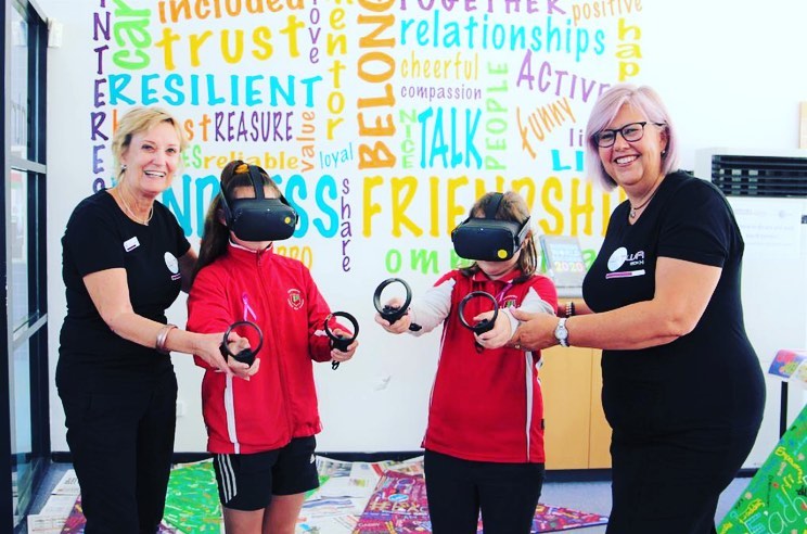 2 WiTWA volunteers assisting 2 students with VR headset technology